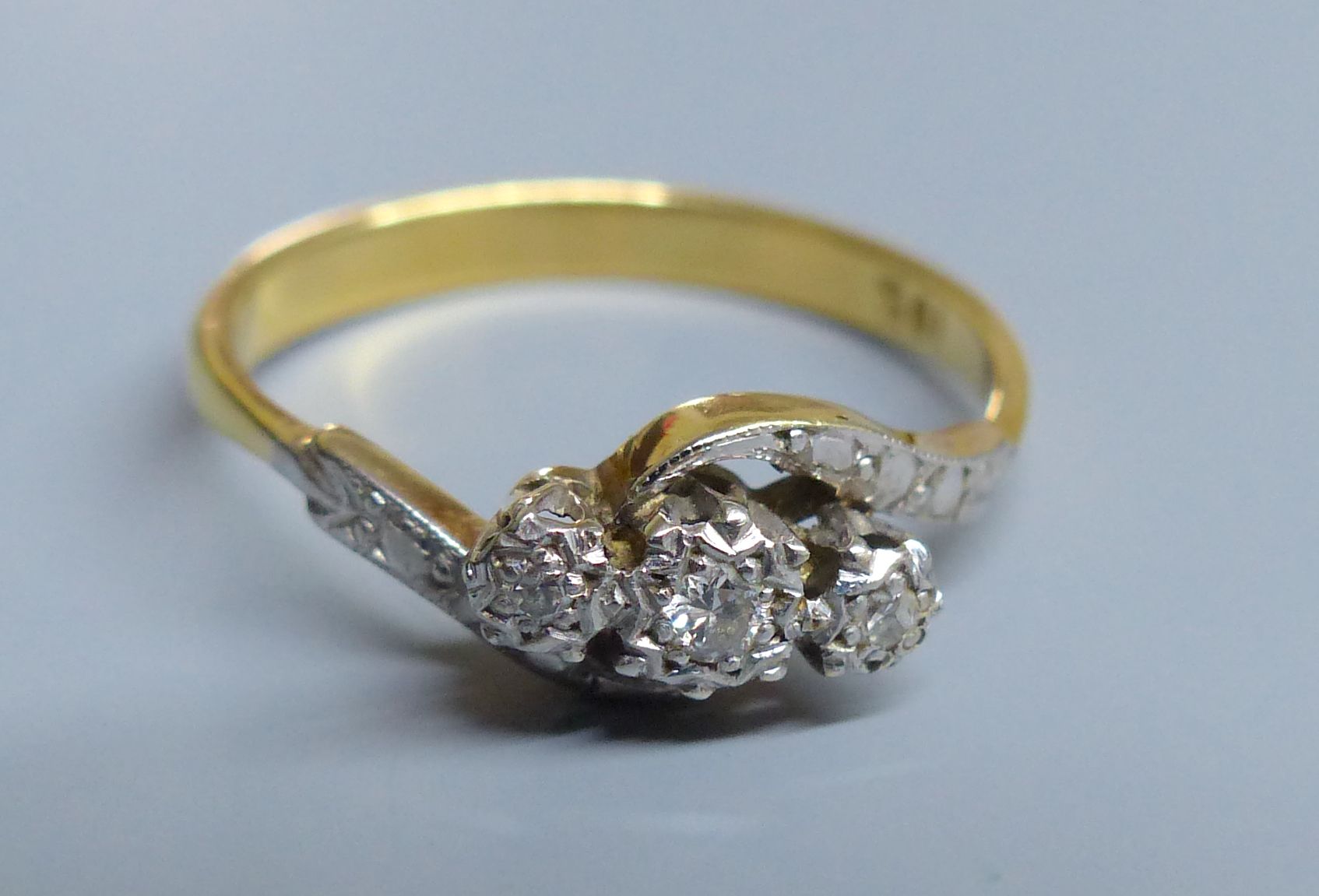 An 18ct and illusion set three stone diamond crossover ring, size R, gross 3.2 grams.